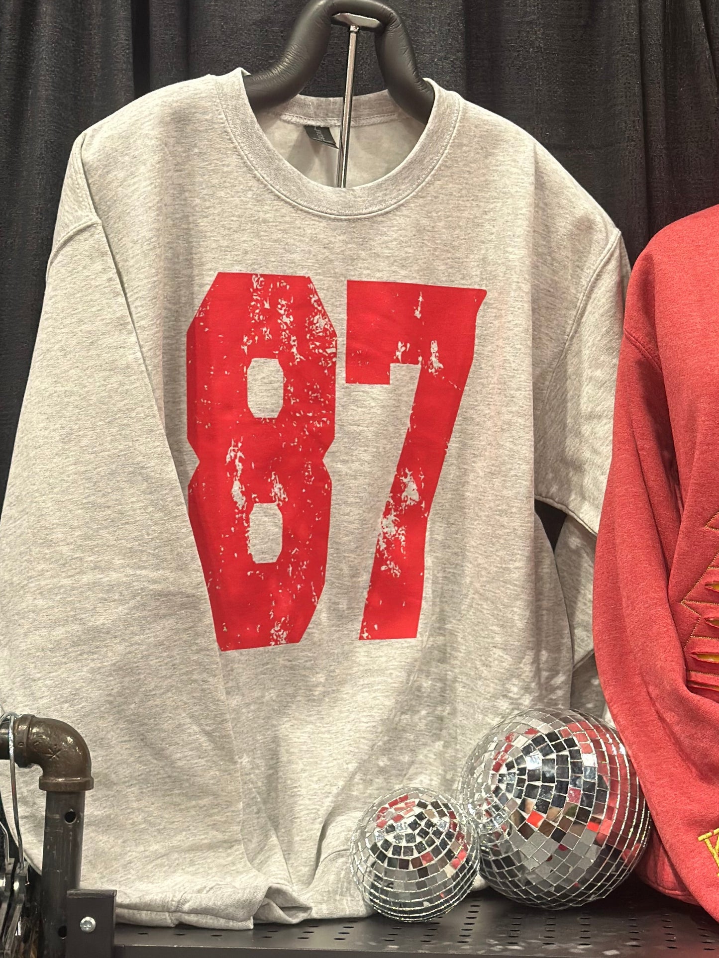 Red and gray t-shirts with visible branding on a black surface.